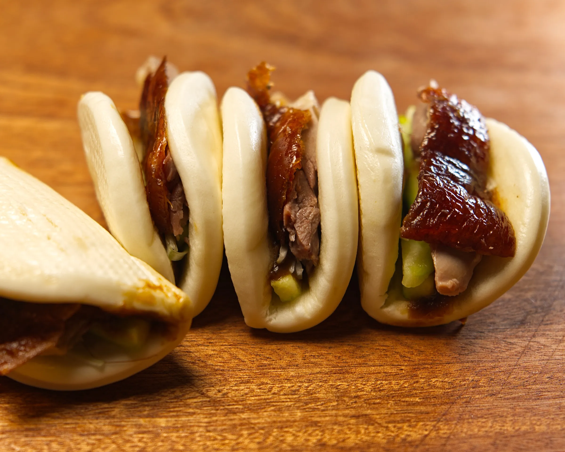 Roast duck bao buns on a wooden board