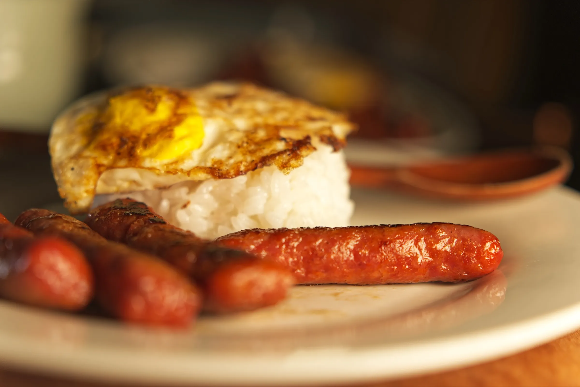 Longganisa, fried egg, and rice in warm golden light
