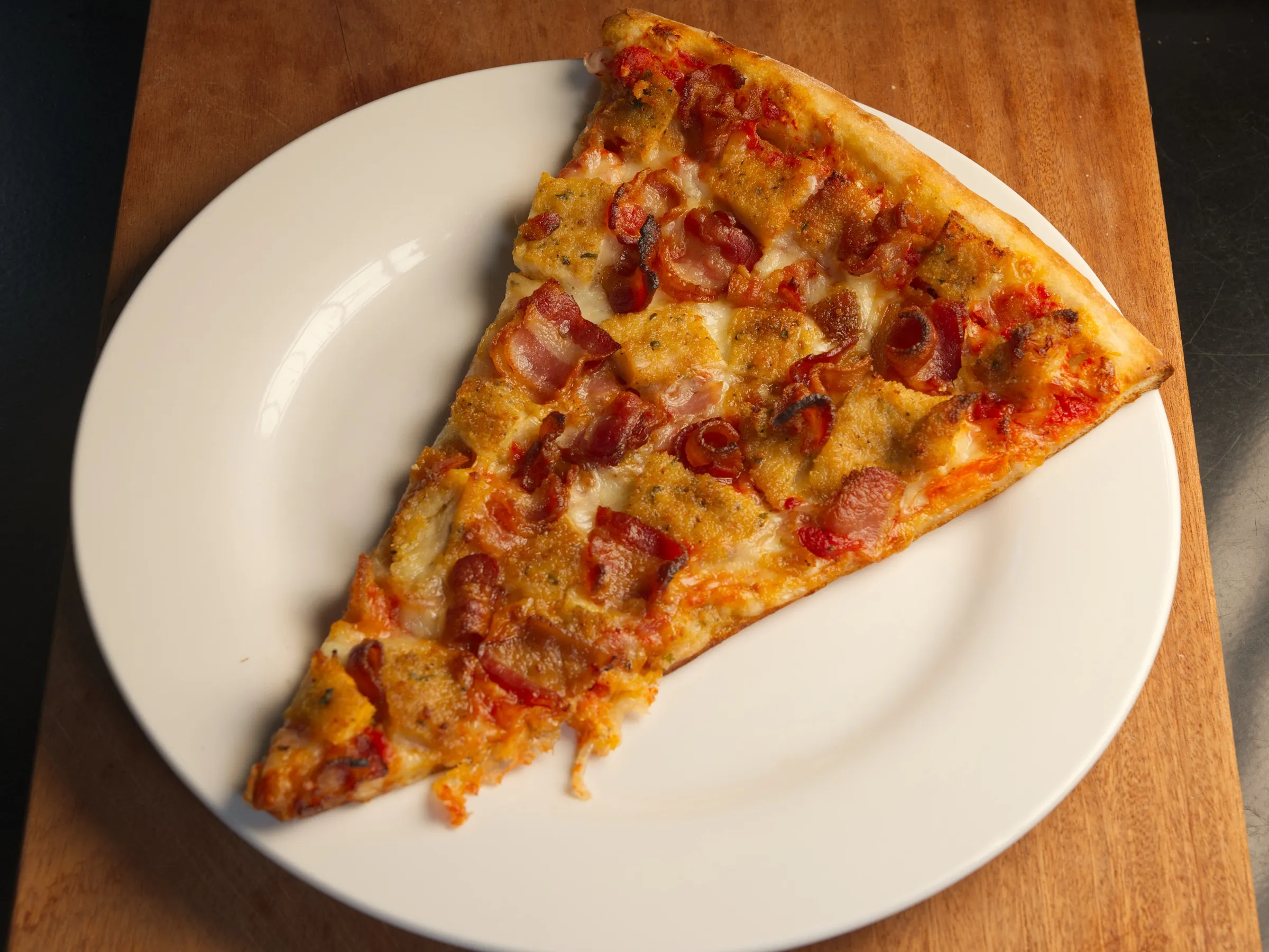 New York–style pizza slice on a white plate